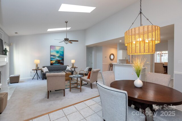 6507 Fairway Point Dr, Charlotte, NC 28269 - dining area featuring a skylight, high vaulted ceiling, light tile patterned floors, a fireplace with flush hearth, and light carpet