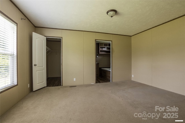 3655 Pinewood Rd, Sumter, SC 29154 - unfurnished bedroom with a decorative wall, a walk in closet, carpet floors, ornamental molding, and ensuite bath