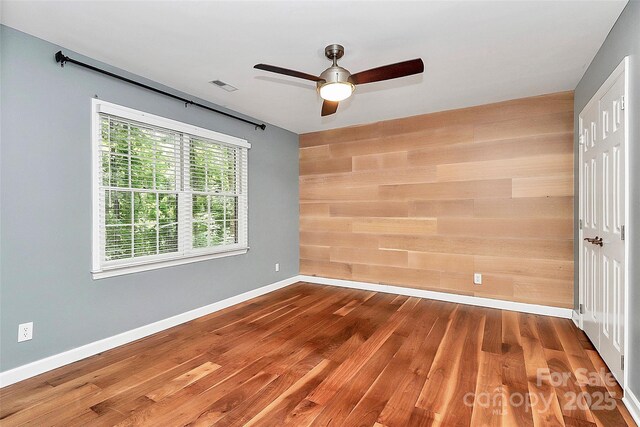 3730 Monique Ln, Charlotte, NC 28210 - unfurnished bedroom with wood finished floors, ceiling fan, wood walls, and a closet