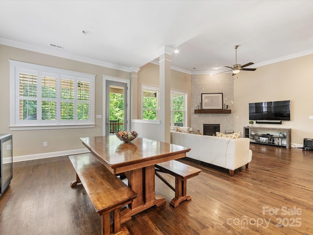 612 Ideal Way, Charlotte, NC 28203 - dining area with ornamental molding, dark wood finished floors, ceiling fan, a large fireplace, and ornate columns