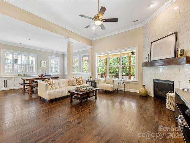 612 Ideal Way, Charlotte, NC 28203 - living area featuring ornamental molding, dark wood finished floors, a tile fireplace, a ceiling fan, and decorative columns