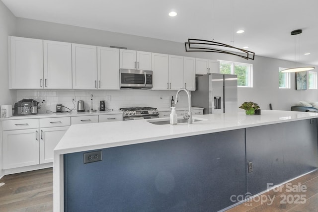 1933 W Trade St, Charlotte, NC 28216 - kitchen featuring appliances with stainless steel finishes, white cabinets, backsplash, wood finished floors, and recessed lighting