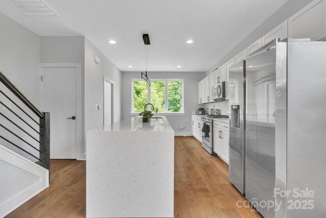 1933 W Trade St, Charlotte, NC 28216 - kitchen featuring stainless steel appliances, a kitchen island, white cabinets, light wood-style floors, and recessed lighting