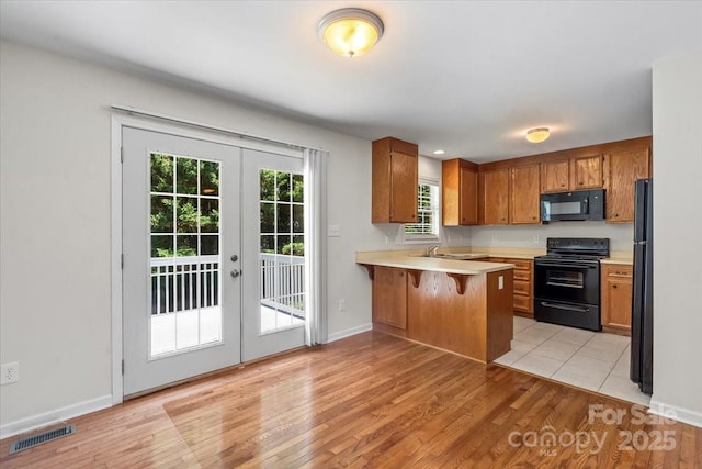 1011 Atherstone St NW, Conover, NC 28613 - kitchen with black appliances, french doors, light countertops, a peninsula, and brown cabinetry