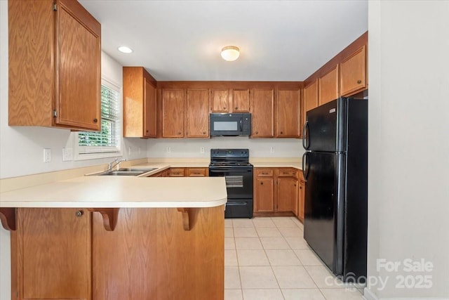 1011 Atherstone St NW, Conover, NC 28613 - kitchen with black appliances, a peninsula, light countertops, brown cabinetry, and light tile patterned floors