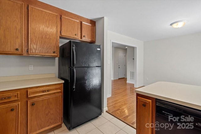 1011 Atherstone St NW, Conover, NC 28613 - kitchen with black appliances, brown cabinets, light tile patterned flooring, and light countertops