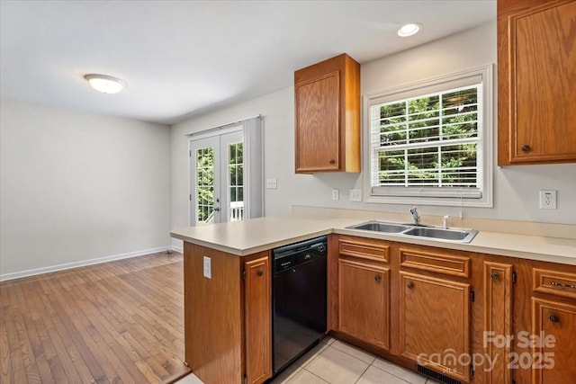 1011 Atherstone St NW, Conover, NC 28613 - kitchen featuring black dishwasher, brown cabinetry, light countertops, a peninsula, and light wood-type flooring