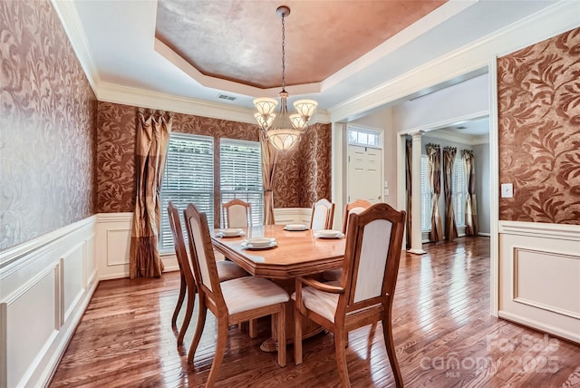 1220 Elrond Dr NW, Charlotte, NC 28269 - dining room featuring wallpapered walls, a chandelier, a raised ceiling, a wainscoted wall, and wood finished floors