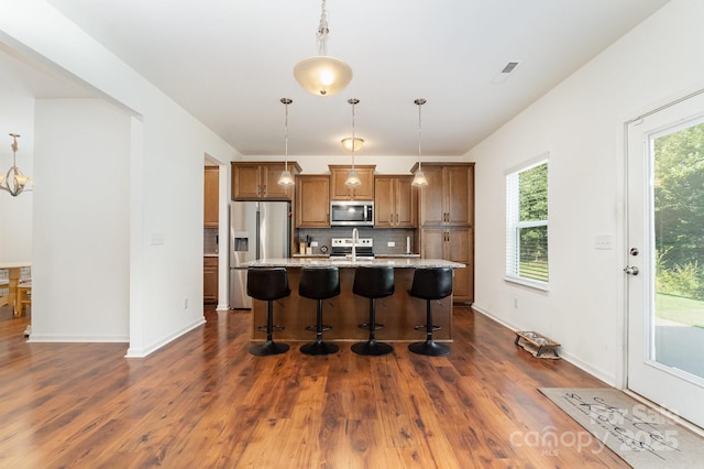 1691 Ashley Lynn Ct, Stanfield, NC 28163 - kitchen with stainless steel appliances, brown cabinetry, a breakfast bar area, a center island with sink, and dark wood finished floors