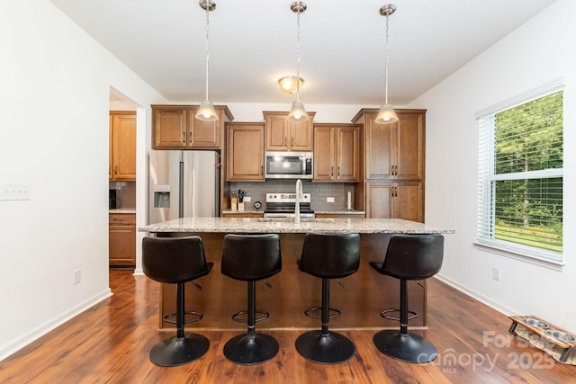 1691 Ashley Lynn Ct, Stanfield, NC 28163 - kitchen featuring stainless steel appliances, brown cabinets, decorative backsplash, and a center island with sink