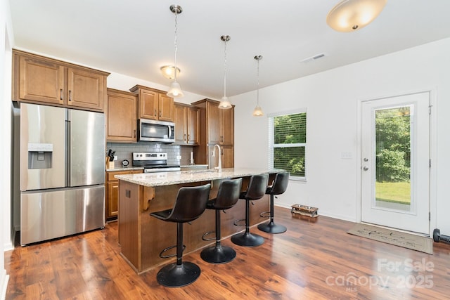 1691 Ashley Lynn Ct, Stanfield, NC 28163 - kitchen with appliances with stainless steel finishes, dark wood-style floors, brown cabinets, and a kitchen island with sink