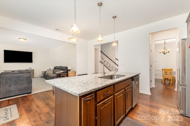 1691 Ashley Lynn Ct, Stanfield, NC 28163 - kitchen featuring appliances with stainless steel finishes, dark wood-type flooring, brown cabinets, light stone countertops, and an island with sink