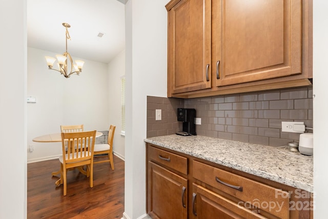 1691 Ashley Lynn Ct, Stanfield, NC 28163 - kitchen with dark wood-style floors, decorative backsplash, light stone countertops, a chandelier, and brown cabinets