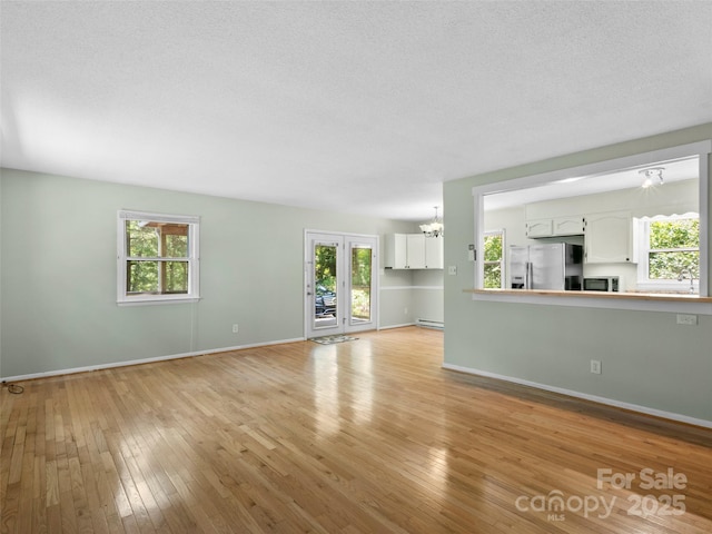 45 Avondale Heights Rd, Asheville, NC 28803 - unfurnished living room with plenty of natural light, a chandelier, and light wood-style flooring