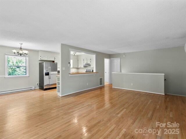 45 Avondale Heights Rd, Asheville, NC 28803 - unfurnished living room with baseboard heating, a chandelier, and light wood-style floors