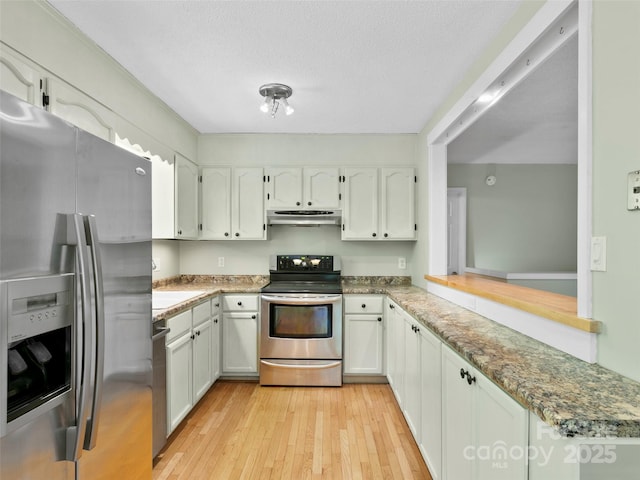 45 Avondale Heights Rd, Asheville, NC 28803 - kitchen with stainless steel appliances, under cabinet range hood, light wood finished floors, white cabinets, and a textured ceiling
