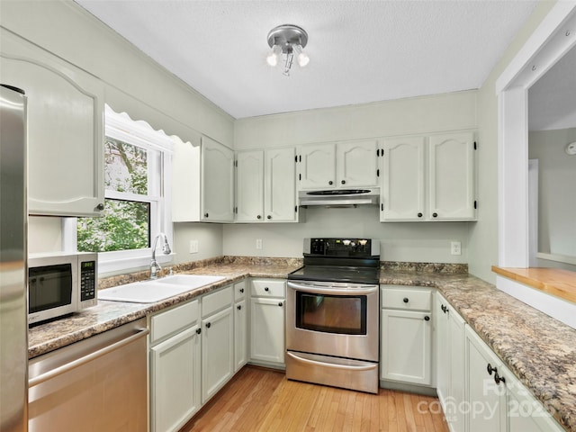 45 Avondale Heights Rd, Asheville, NC 28803 - kitchen with under cabinet range hood, stainless steel appliances, light wood-style floors, white cabinets, and a textured ceiling