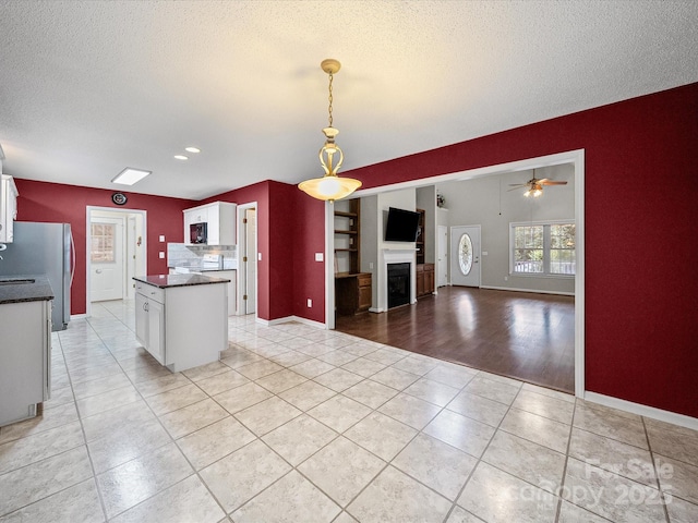 179 Delwood Ct, Mount Gilead, NC 27371 - kitchen featuring dark countertops, white cabinetry, light tile patterned floors, a textured ceiling, and freestanding refrigerator