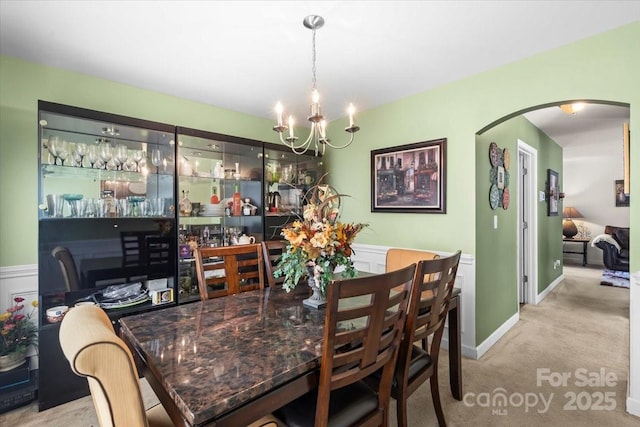 9511 Turning Wheel Dr, Charlotte, NC 28214 - dining area featuring arched walkways, a chandelier, carpet floors, and wainscoting