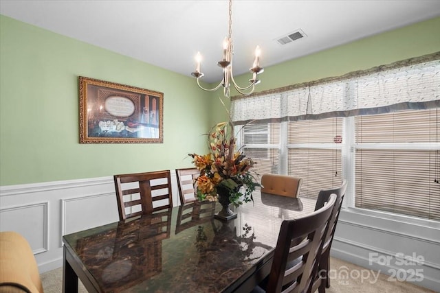 9511 Turning Wheel Dr, Charlotte, NC 28214 - carpeted dining area with a chandelier, wainscoting, and a decorative wall