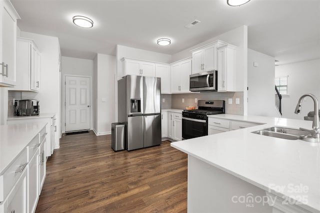 9529 Cotswood Pl, Gastonia, NC 28056 - kitchen with stainless steel appliances, decorative backsplash, dark wood-style floors, white cabinetry, and light countertops