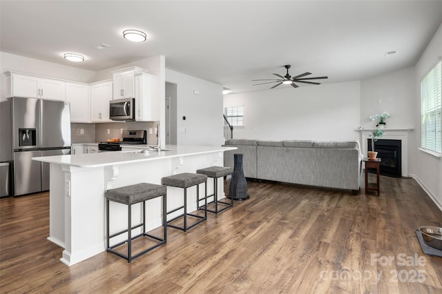 9529 Cotswood Pl, Gastonia, NC 28056 - kitchen featuring stainless steel appliances, a breakfast bar, dark wood-style flooring, light countertops, and white cabinetry