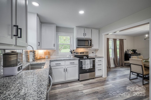 110 Camelot Dr, Granite Falls, NC 28630 - kitchen featuring appliances with stainless steel finishes, decorative backsplash, light wood-style floors, white cabinetry, and light stone counters