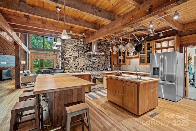 574 Locust Grove Dr, Waynesville, NC 28785 - kitchen featuring stainless steel appliances, butcher block countertops, wall chimney range hood, an island with sink, and light wood finished floors