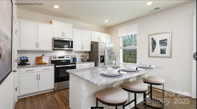 233 Paige Rd, Kings Mountain, NC 28086 - kitchen with stainless steel appliances, a kitchen bar, a center island with sink, backsplash, and white cabinets