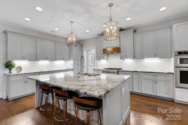 2122 Goose Creek Farm Ln, Indian Trail, NC 28079 - kitchen with a chandelier, stainless steel appliances, an island with sink, backsplash, and premium range hood