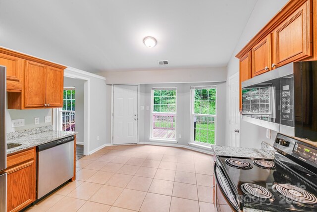 9000 Vagabond Rd, Charlotte, NC 28227 - kitchen with appliances with stainless steel finishes, light stone counters, brown cabinets, light tile patterned floors, and lofted ceiling