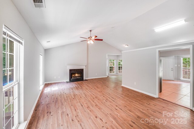 9000 Vagabond Rd, Charlotte, NC 28227 - unfurnished living room with light wood-style flooring, plenty of natural light, vaulted ceiling, a fireplace with flush hearth, and a ceiling fan