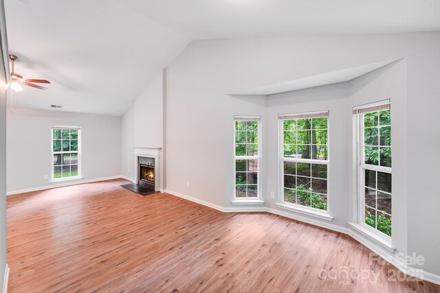 9000 Vagabond Rd, Charlotte, NC 28227 - unfurnished living room featuring light wood-type flooring, vaulted ceiling, ceiling fan, and a warm lit fireplace