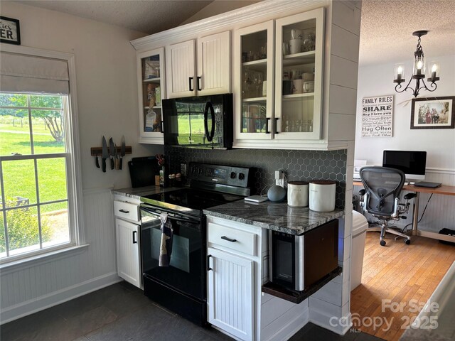 8122 Hutchison Ln, Vale, NC 28168 - kitchen with black appliances, wainscoting, healthy amount of natural light, glass insert cabinets, and dark stone counters
