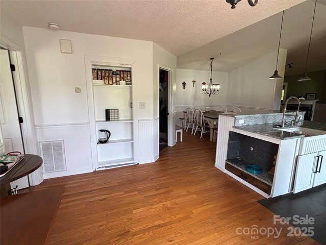 8122 Hutchison Ln, Vale, NC 28168 - kitchen featuring wood finished floors, a wainscoted wall, a chandelier, a textured ceiling, and pendant lighting