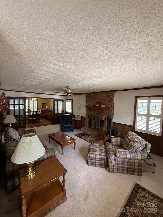 200 Breslin St, Wadesboro, NC 28170 - living room featuring a textured ceiling, a ceiling fan, a wainscoted wall, wood walls, and a brick fireplace