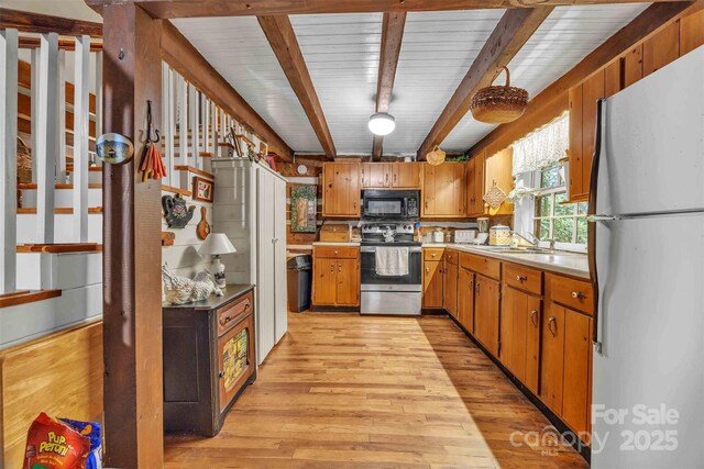 189 Woodstock Dr, West Jefferson, NC 28694 - kitchen with freestanding refrigerator, stainless steel electric range oven, black microwave, light wood-style floors, and brown cabinets