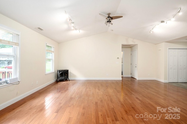 29 Honey Hollow Ln, Fairview, NC 28730 - empty room with track lighting, a wood stove, a ceiling fan, vaulted ceiling, and light wood-style floors