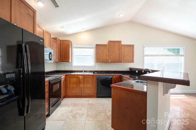 29 Honey Hollow Ln, Fairview, NC 28730 - kitchen with black appliances, a peninsula, a kitchen bar, brown cabinetry, and lofted ceiling
