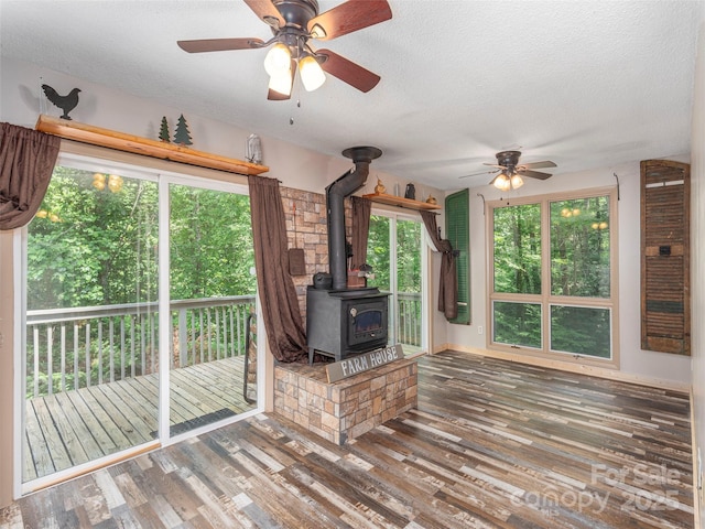1131 Laurel Branch Rd, Waynesville, NC 28785 - unfurnished living room featuring a wood stove, a textured ceiling, a ceiling fan, wood finished floors, and plenty of natural light