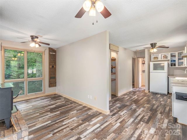 1131 Laurel Branch Rd, Waynesville, NC 28785 - kitchen featuring freestanding refrigerator, ceiling fan, a wood stove, and a textured ceiling
