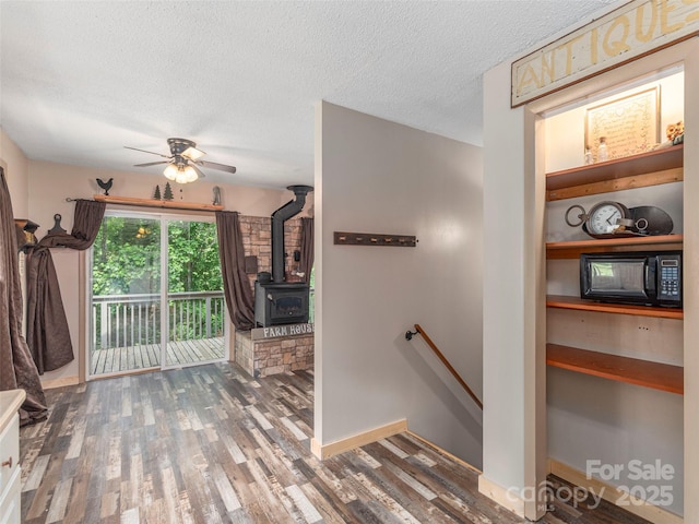 1131 Laurel Branch Rd, Waynesville, NC 28785 - stairway featuring wood finished floors, ceiling fan, a wood stove, and a textured ceiling