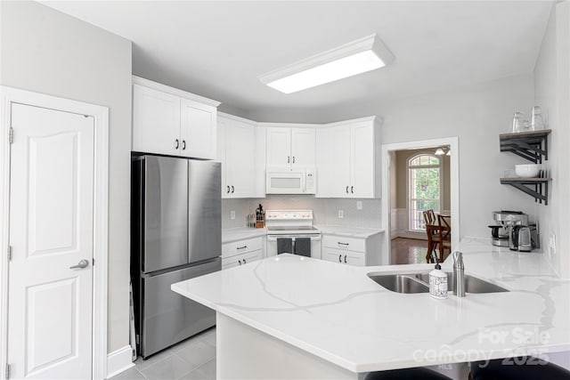 4605 Sarandon Ct, Charlotte, NC 28215 - kitchen with white appliances, a peninsula, white cabinetry, light stone counters, and backsplash