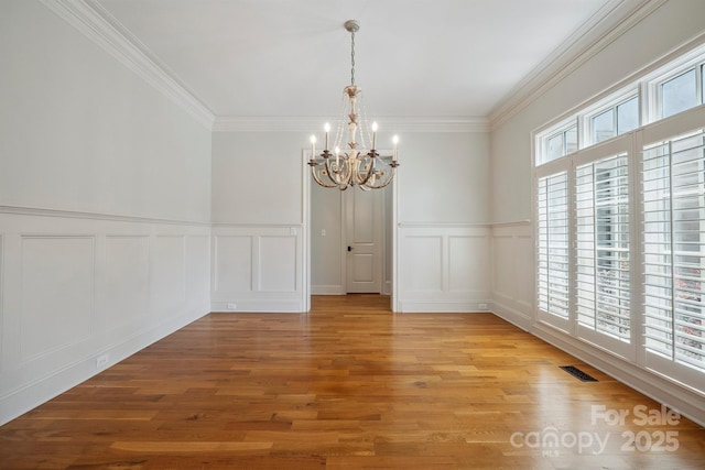 20635 Queensdale Dr, Cornelius, NC 28031 - unfurnished room featuring a chandelier, a decorative wall, light wood-style flooring, crown molding, and a wainscoted wall