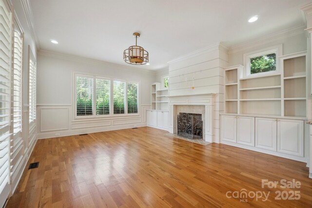 20635 Queensdale Dr, Cornelius, NC 28031 - unfurnished living room with plenty of natural light, a premium fireplace, light wood-style floors, a chandelier, and wainscoting