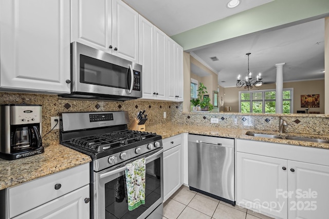 4854 S Hill View Dr, Charlotte, NC 28210 - kitchen with appliances with stainless steel finishes, a chandelier, decorative backsplash, light tile patterned flooring, and light stone counters