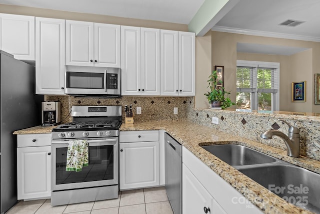 4854 S Hill View Dr, Charlotte, NC 28210 - kitchen with stainless steel appliances, white cabinetry, tasteful backsplash, ornamental molding, and light tile patterned floors