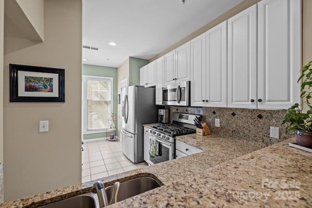 4854 S Hill View Dr, Charlotte, NC 28210 - kitchen with stainless steel appliances, light stone countertops, white cabinets, light tile patterned floors, and decorative backsplash