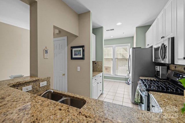 4854 S Hill View Dr, Charlotte, NC 28210 - kitchen with appliances with stainless steel finishes, light stone countertops, light tile patterned floors, white cabinets, and backsplash