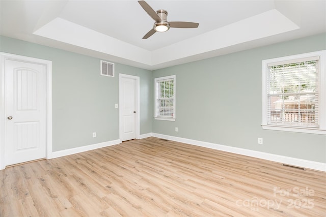 43 Paddington Dr SW, Concord, NC 28025 - unfurnished bedroom with a tray ceiling, multiple windows, and light wood-type flooring